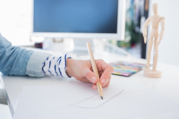 Female hands drawing with pencil on paper on her desk